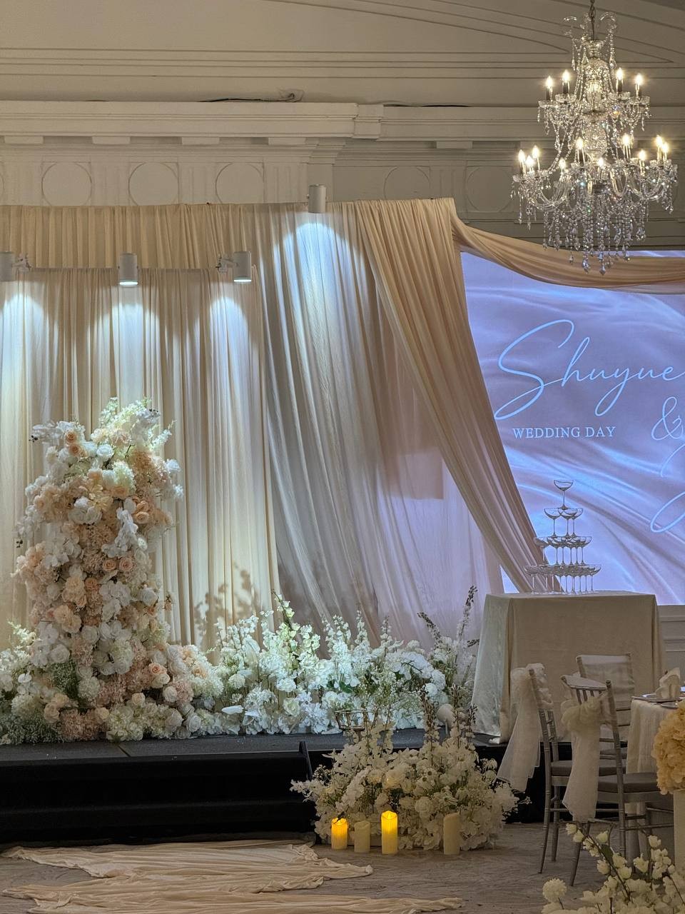 The softly draped ballroom stage and abundant pale flowers