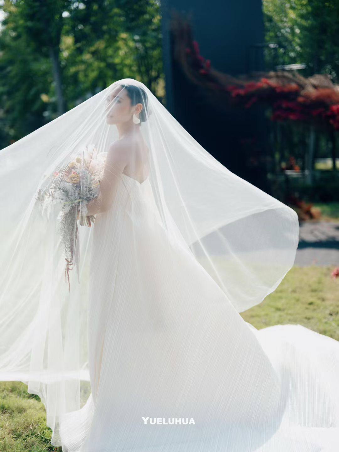 The bride beneath a flowing white veil in the garden