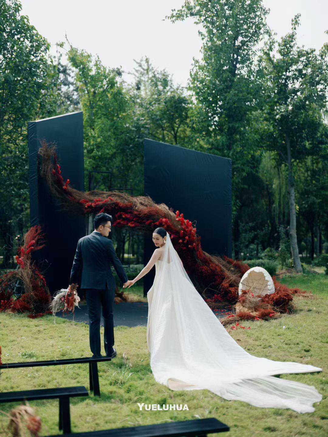 The couple before charcoal panels crossed by crimson flowers