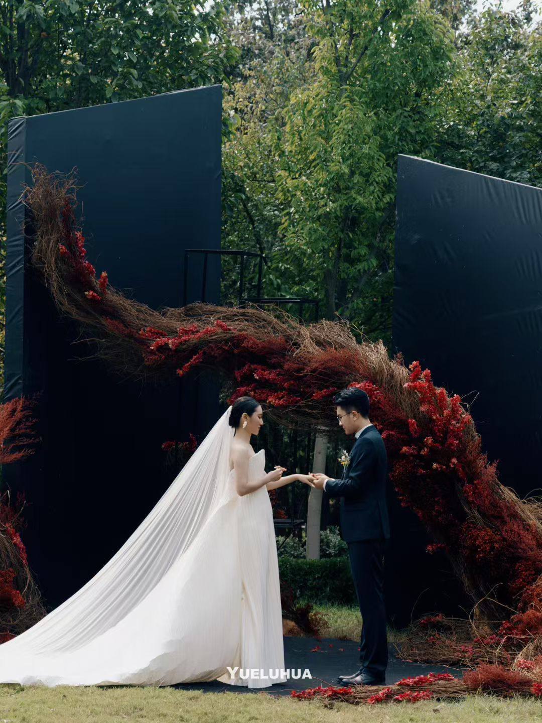 The couple facing each other before dark architectural panels