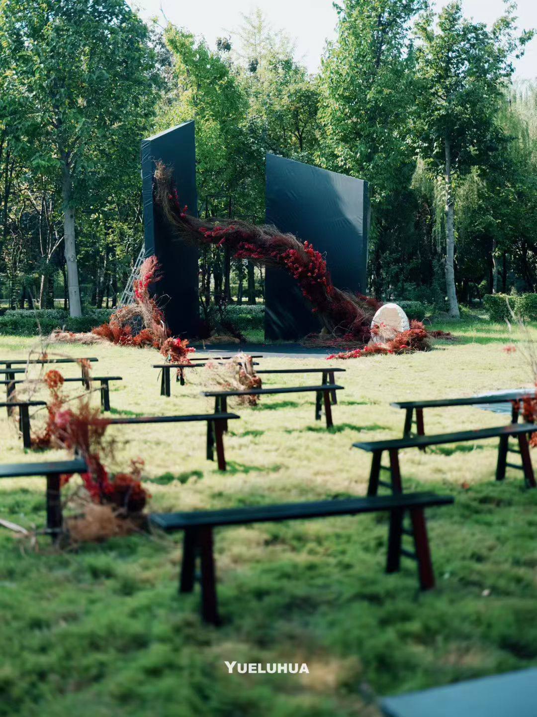 Low ceremony benches facing the charcoal and crimson installation