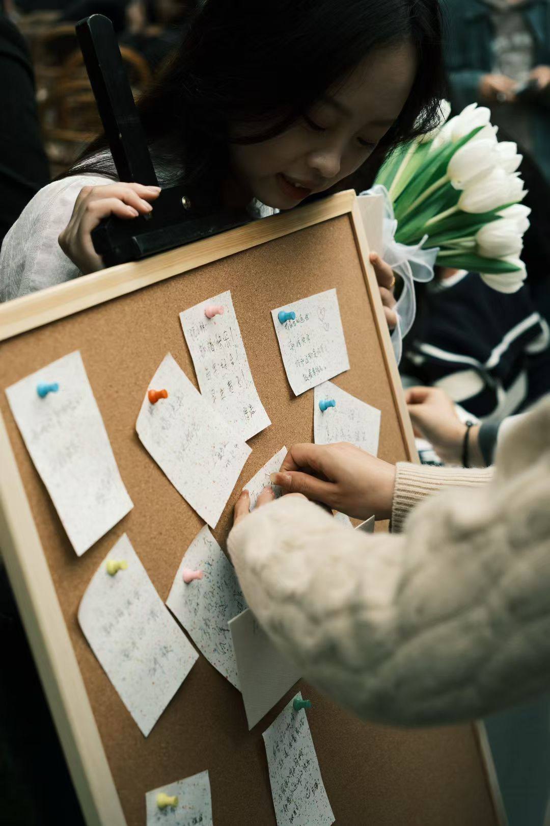 A guest placing a handwritten note on a display board