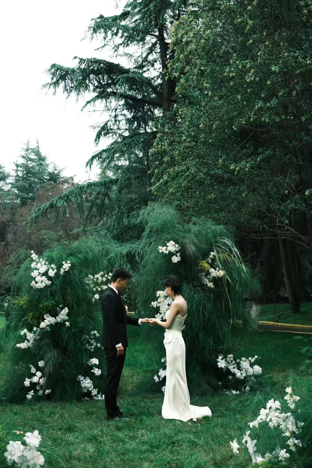 The couple surrounded by white flowers beneath garden trees
