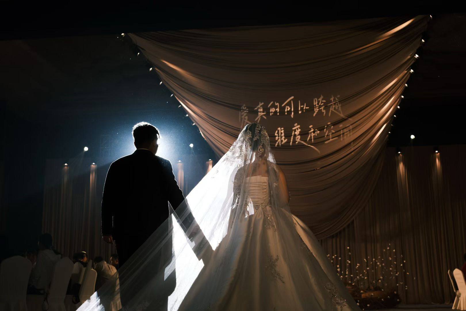 The couple beneath sculptural brown drapery in a beam of light