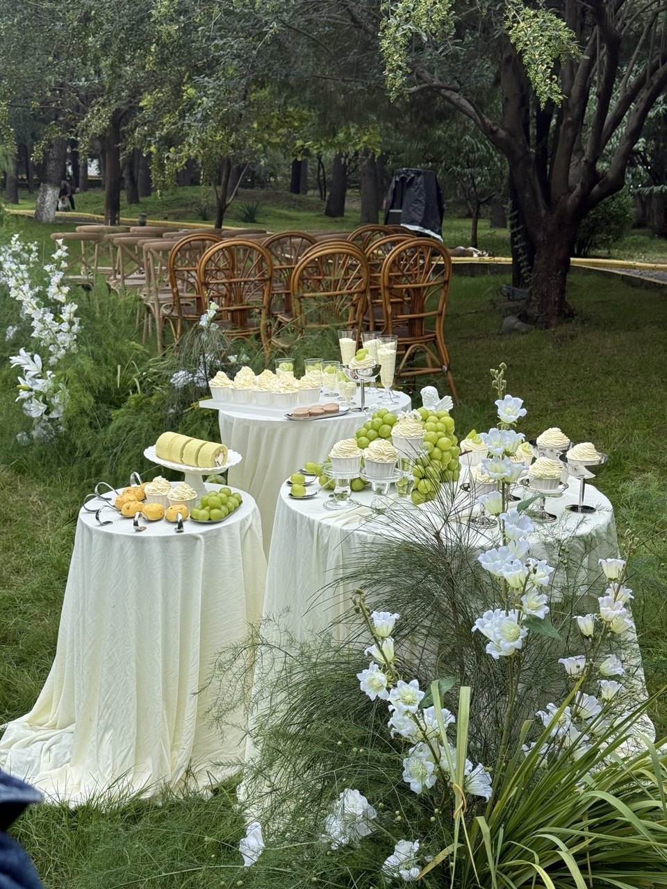 A white-draped table with flowers and refreshments in the garden