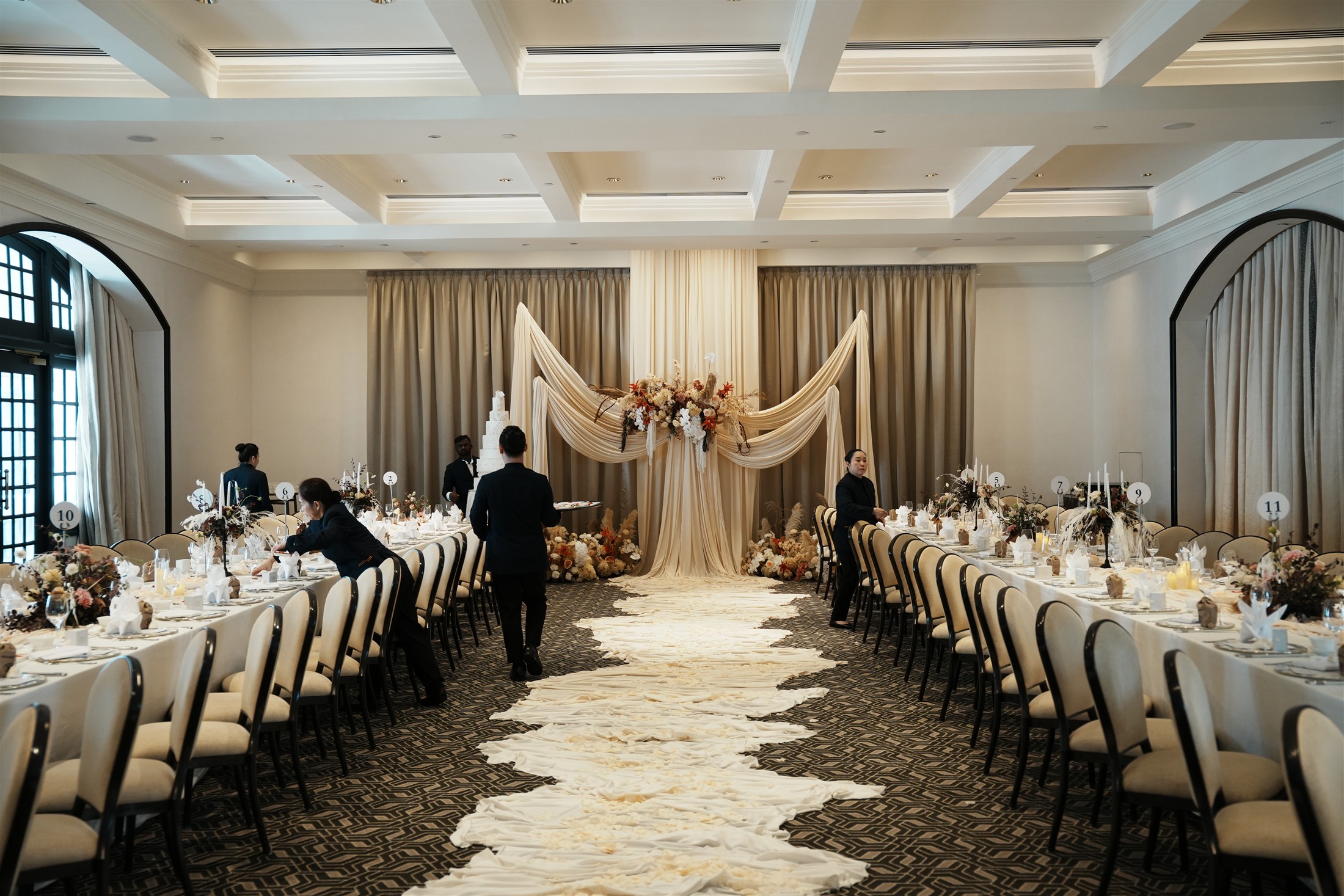 The full room with flowing aisle fabric and long dining tables